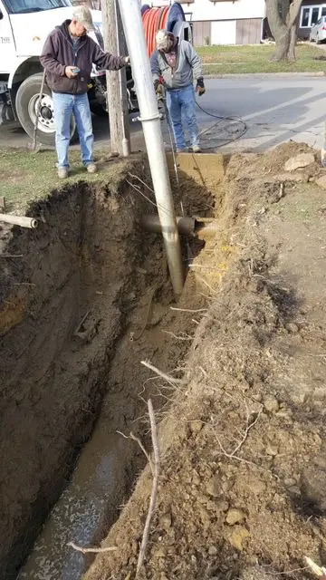 A hole dug in the ground with people standing around.