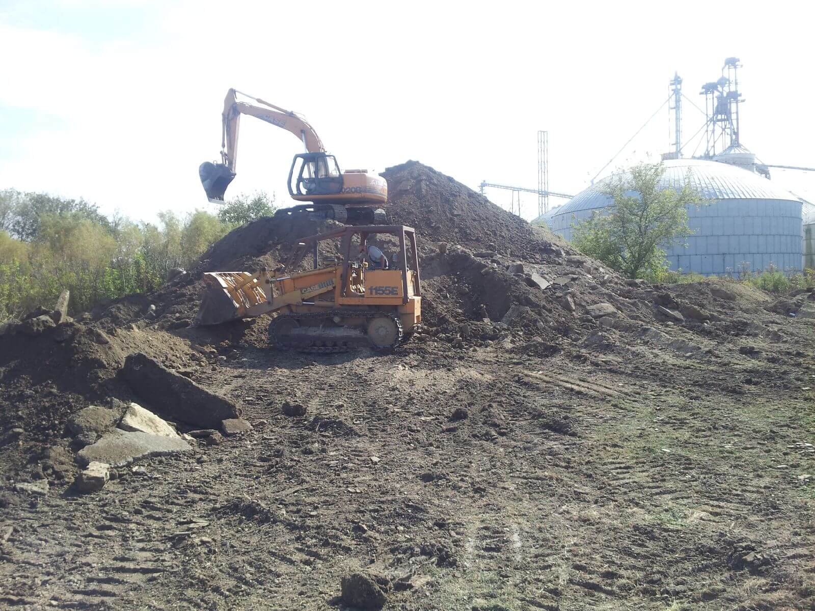 A large pile of dirt with a tractor in the background.