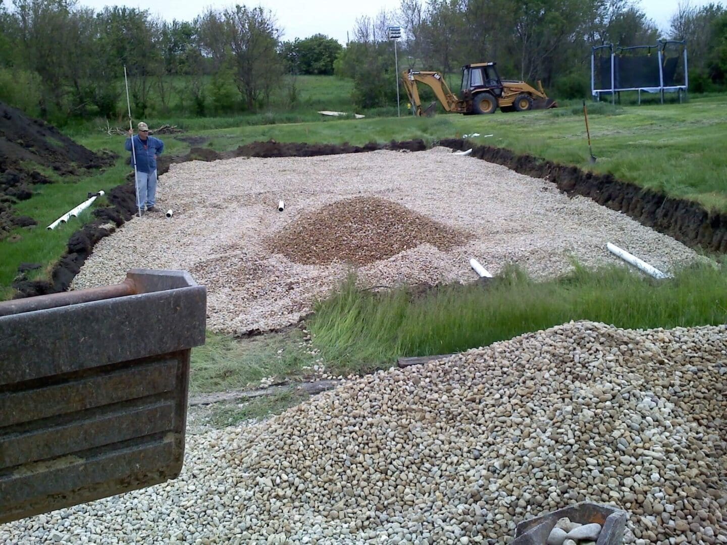 A man standing in the dirt next to a pile of gravel.