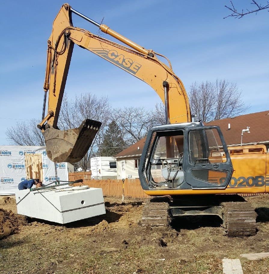 A yellow and black excavator on top of grass.